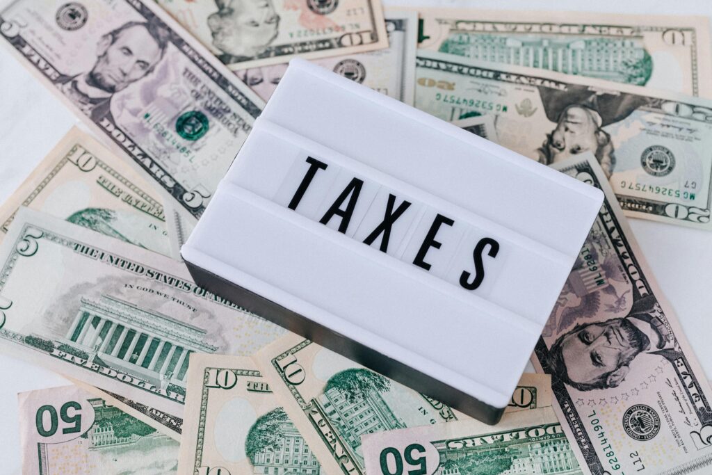pexels-photo-4386367-4386367 US dollar bills surrounding a sign showing 'TAXES'. Ideal for financial context.